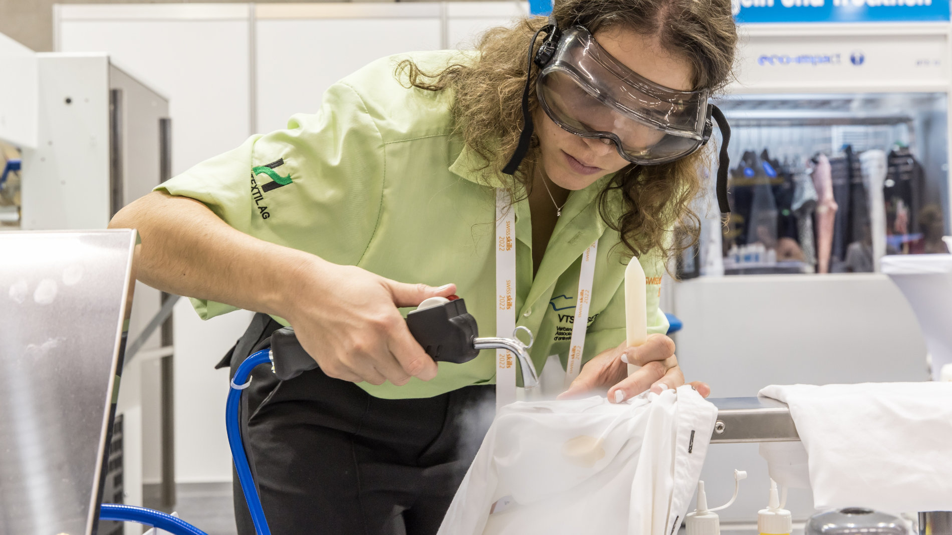 Competitor at the Swiss Textile Care Championships removing stains from a white shirt with a steam cleaning device.